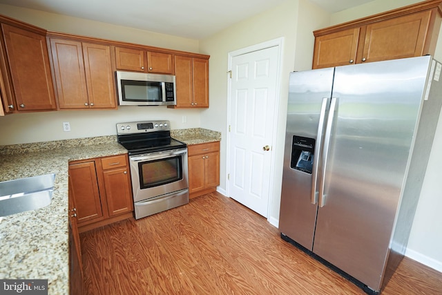 1322 Aspen Dr, Salisbury, MD 21804 - kitchen with appliances with stainless steel finishes, light wood-style floors, brown cabinetry, and light stone countertops