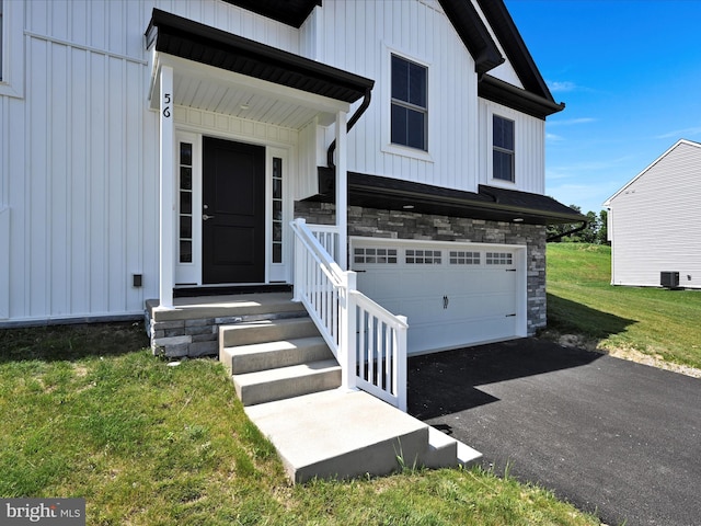 564 Monocacy Trl, Spring Grove, PA 17362 - doorway to property featuring board and batten siding, stone siding, asphalt driveway, an attached garage, and a yard