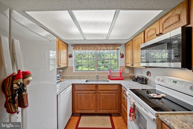 119 Prosperity Ave SE Unit C, Leesburg, VA 20175 - kitchen with white appliances, light wood-type flooring, decorative backsplash, brown cabinetry, and light stone countertops