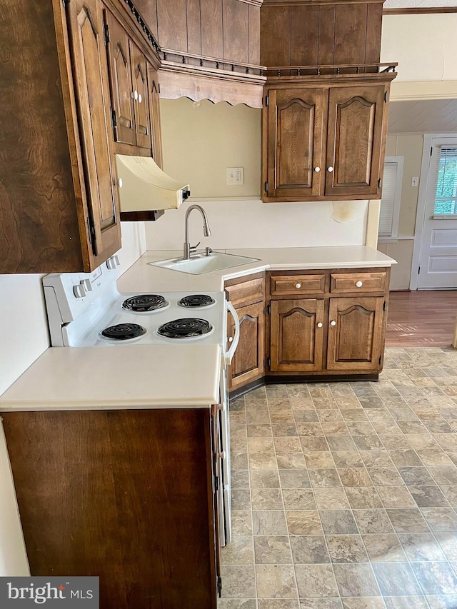 363 New St, Pottstown, PA 19464 - kitchen with range hood, light countertops, white range with electric cooktop, stone finish floors, and brown cabinetry