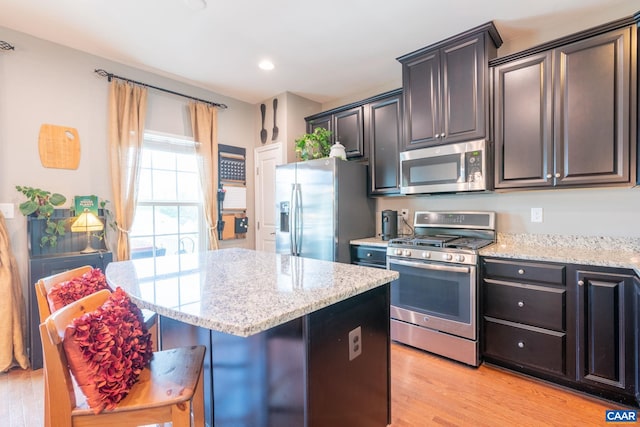 2140 Elm Tree Knl, Charlottesville, VA 22911 - kitchen with appliances with stainless steel finishes, a kitchen island, light wood finished floors, light stone counters, and a breakfast bar