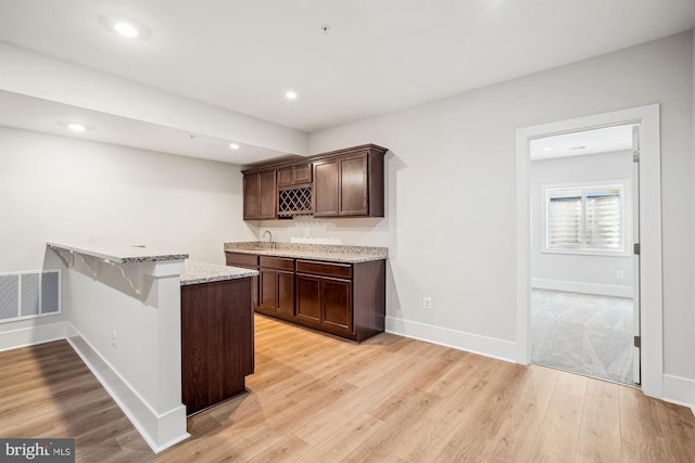 3904 Diplomat Ave, Bowie, MD 20721 - kitchen with light stone counters, light wood-type flooring, dark brown cabinets, recessed lighting, and a peninsula