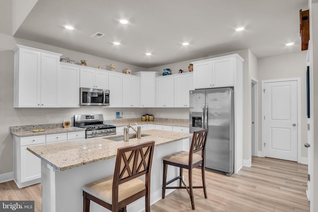 43 Boneset Dr, Gettysburg, PA 17325 - kitchen with appliances with stainless steel finishes, light wood-style floors, a breakfast bar area, white cabinets, and a kitchen island with sink