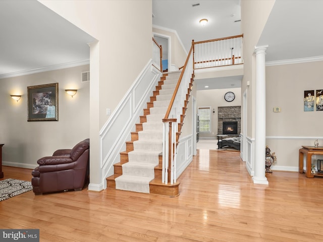 6720 Walter Scott Way, Columbia, MD 21044 - entrance foyer with light wood finished floors, ornate columns, a stone fireplace, stairs, and crown molding