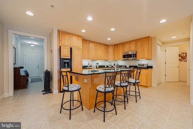 301 14th St Unit 304, Ocean City, MD 21842 - kitchen featuring stainless steel microwave, light tile patterned flooring, recessed lighting, a kitchen island with sink, and a breakfast bar area