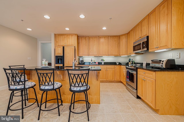 301 14th St Unit 304, Ocean City, MD 21842 - kitchen featuring appliances with stainless steel finishes, recessed lighting, light tile patterned floors, a kitchen island with sink, and a breakfast bar area