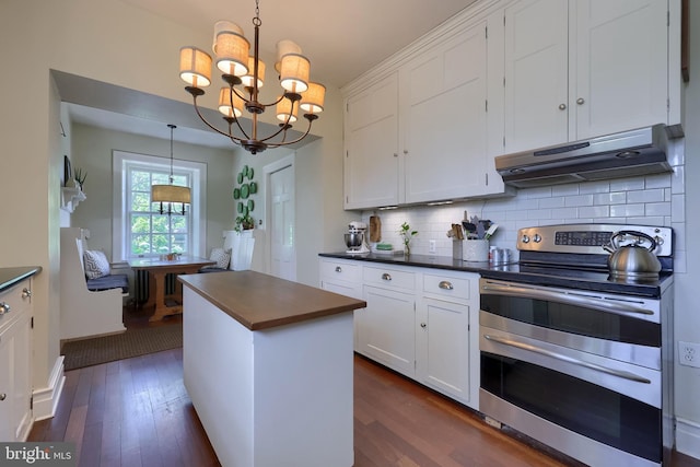 152 Main St, New Providence, PA 17560 - kitchen with range with two ovens, under cabinet range hood, white cabinets, a chandelier, and dark wood-style flooring
