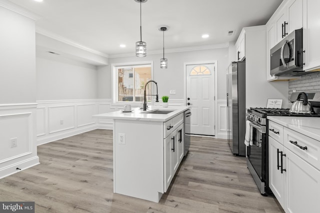 233 S Clinton St, Baltimore, MD 21224 - kitchen featuring stainless steel appliances, recessed lighting, a center island with sink, ornamental molding, and a wainscoted wall