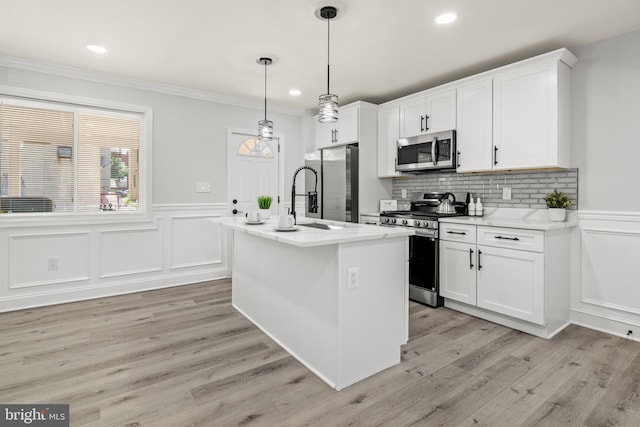 233 S Clinton St, Baltimore, MD 21224 - kitchen featuring stainless steel appliances, a center island with sink, a decorative wall, a wainscoted wall, and white cabinetry