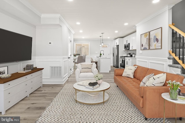 233 S Clinton St, Baltimore, MD 21224 - living room featuring crown molding, light wood-style floors, stairs, recessed lighting, and a wainscoted wall
