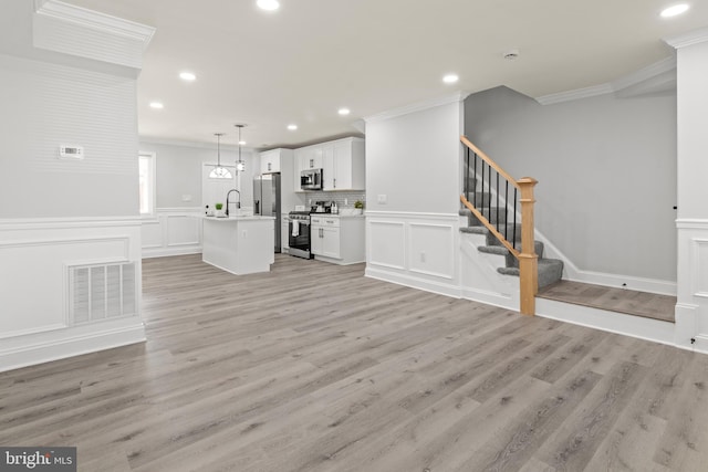 233 S Clinton St, Baltimore, MD 21224 - unfurnished living room with crown molding, a decorative wall, stairs, light wood-style floors, and recessed lighting