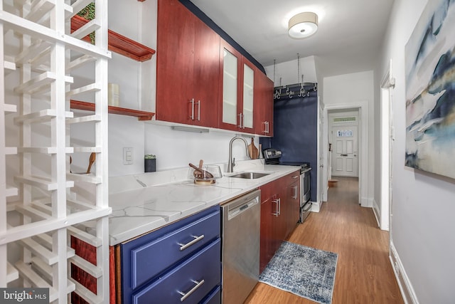 1217 Holbrook St NE, Washington, DC 20002 - kitchen with appliances with stainless steel finishes, blue cabinets, light wood finished floors, glass insert cabinets, and light stone countertops