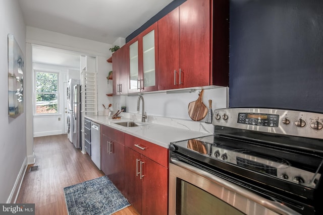 1217 Holbrook St NE, Washington, DC 20002 - kitchen featuring appliances with stainless steel finishes, light wood finished floors, light countertops, glass insert cabinets, and dark brown cabinets