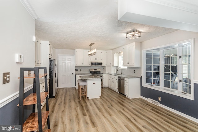421 Dart Dr, Hanover, PA 17331 - kitchen featuring appliances with stainless steel finishes, white cabinets, a breakfast bar area, a center island, and a textured ceiling