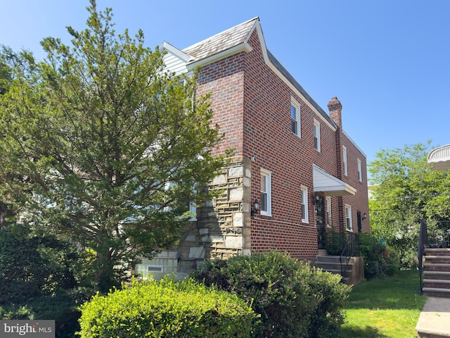 8016 Hollis St, Philadelphia, PA 19150 - view of side of home featuring brick siding, a lawn, a chimney, and a high end roof