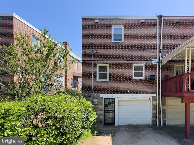 8016 Hollis St, Philadelphia, PA 19150 - back of property featuring an attached garage, brick siding, driveway, and stone siding