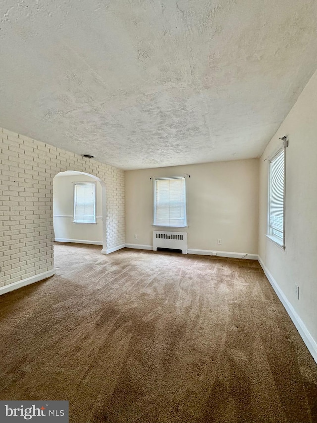 3913 Loch Raven Blvd, Baltimore, MD 21218 - unfurnished living room with radiator heating unit, a textured ceiling, plenty of natural light, carpet floors, and arched walkways