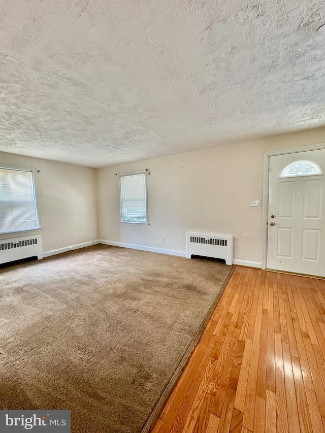3913 Loch Raven Blvd, Baltimore, MD 21218 - unfurnished living room featuring radiator heating unit, a textured ceiling, and hardwood / wood-style flooring