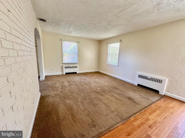 3913 Loch Raven Blvd, Baltimore, MD 21218 - unfurnished living room featuring radiator heating unit, a textured ceiling, and wood finished floors