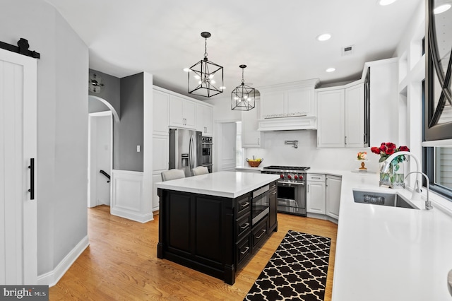 75 Bittersweet Dr, Doylestown, PA 18901 - kitchen with stainless steel appliances, dark cabinetry, custom exhaust hood, light countertops, and light wood-style floors