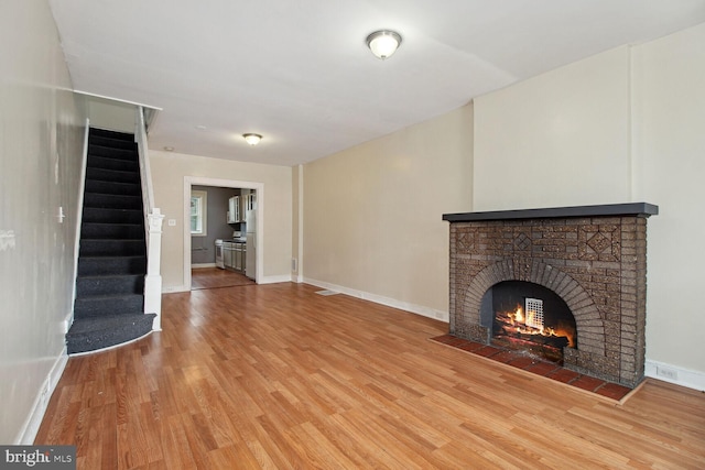 736 Bartlett Ave, Baltimore, MD 21218 - unfurnished living room with light wood-style flooring, stairs, and a fireplace