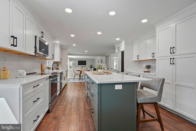 7728 Barnstable Pl, Rockville, MD 20855 - kitchen with stainless steel appliances, white cabinetry, open floor plan, a kitchen bar, and recessed lighting