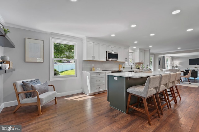 7728 Barnstable Pl, Rockville, MD 20855 - kitchen with appliances with stainless steel finishes, a breakfast bar, light countertops, white cabinets, and dark wood finished floors