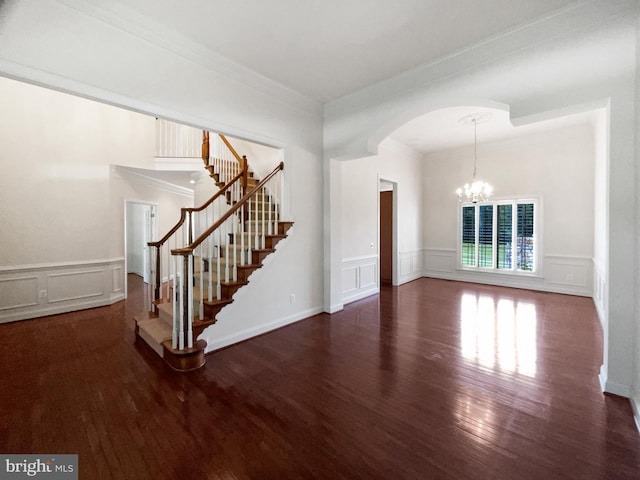 12054 Greatbridge Rd, Woodbridge, VA 22192 - unfurnished living room featuring a decorative wall, stairs, wood finished floors, a chandelier, and arched walkways