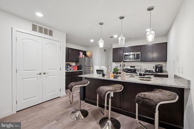 3104 N Broad St, Philadelphia, PA 19132 - kitchen with appliances with stainless steel finishes, a breakfast bar, light wood-style floors, light stone countertops, and recessed lighting