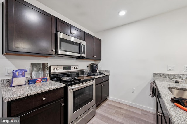 3104 N Broad St, Philadelphia, PA 19132 - kitchen featuring appliances with stainless steel finishes, light wood-style floors, dark brown cabinetry, light stone counters, and recessed lighting