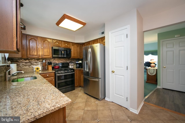 9 Stirrup Way, Burlington, NJ 08016 - kitchen with appliances with stainless steel finishes, brown cabinetry, light stone counters, backsplash, and light tile patterned floors