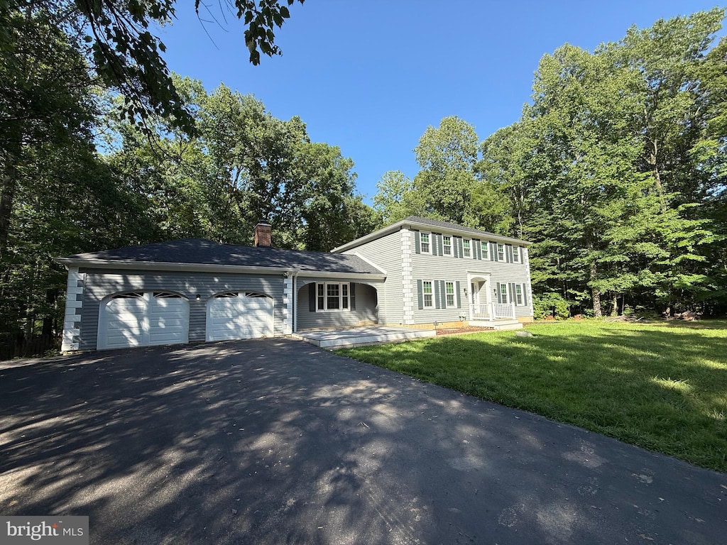 4910 Stonehurst Dr, Woodbridge, VA 22192 - colonial house with asphalt driveway, an attached garage, a chimney, and a front lawn