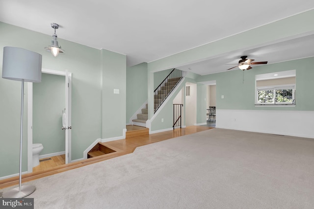 8916 Rosewood Way, Jessup, MD 20794 - unfurnished living room with carpet flooring, stairs, ceiling fan, and wood finished floors