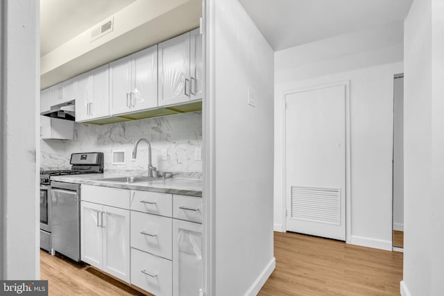 3100 S Manchester St Unit 827, Falls Church, VA 22044 - kitchen featuring white cabinets, appliances with stainless steel finishes, tasteful backsplash, and light wood-type flooring