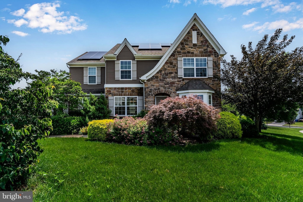 318 Woodbridge Dr, Etters, PA 17319 - view of front of house featuring stone siding, a front yard, and solar panels