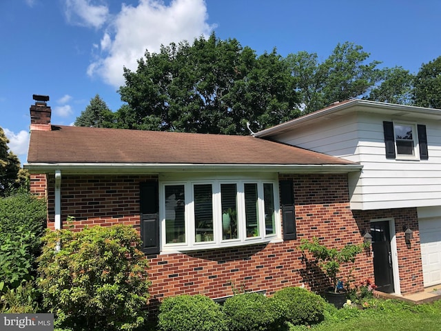 2714 Whitney Dr, York, PA 17402 - view of side of home with brick siding, a chimney, and a garage