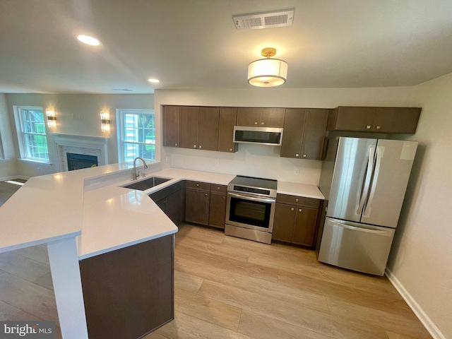 101 Lexington Way, Morgantown, PA 19543 - kitchen with appliances with stainless steel finishes, light countertops, dark brown cabinets, a peninsula, and a fireplace