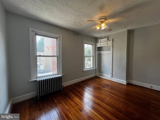 453 Belgrade St, Philadelphia, PA 19125 - unfurnished bedroom featuring radiator, a textured ceiling, hardwood / wood-style floors, multiple windows, and a closet