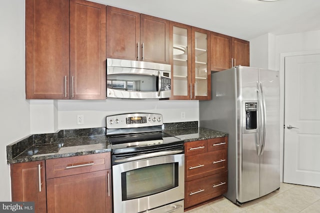 157 Fleet St Unit 303, National Harbor, MD 20745 - kitchen with appliances with stainless steel finishes, glass insert cabinets, dark stone countertops, light tile patterned floors, and brown cabinets