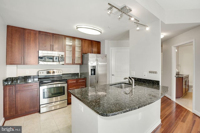 157 Fleet St Unit 303, National Harbor, MD 20745 - kitchen featuring stainless steel appliances, a peninsula, glass insert cabinets, dark stone counters, and light wood-style floors