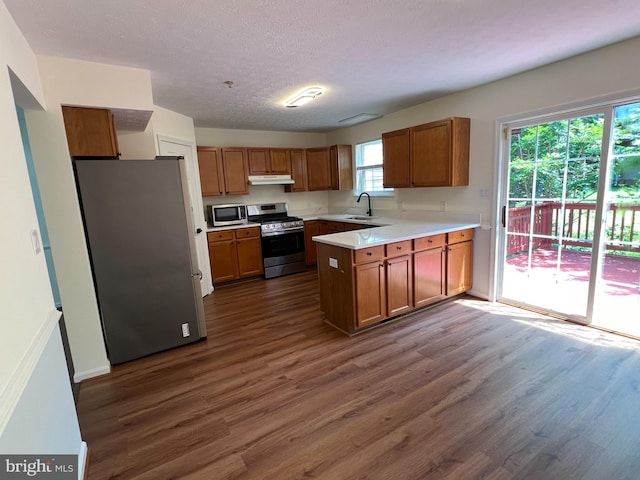 4407 Stanford Ct, Owings Mills, MD 21117 - kitchen featuring stainless steel appliances, dark wood-style floors, under cabinet range hood, brown cabinets, and a textured ceiling