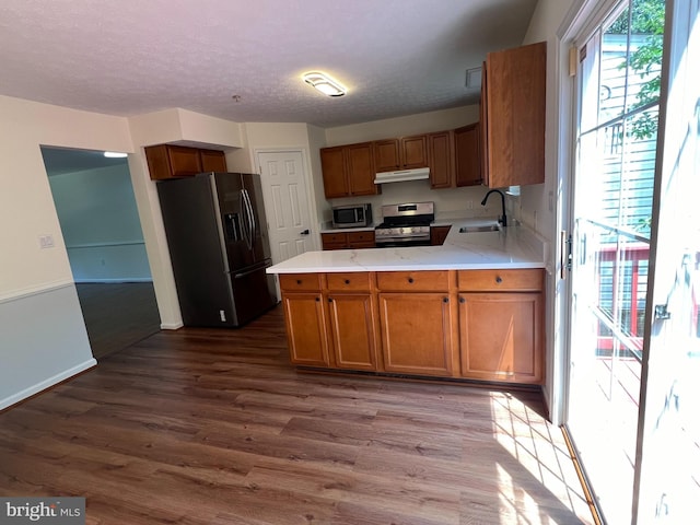 4407 Stanford Ct, Owings Mills, MD 21117 - kitchen with appliances with stainless steel finishes, under cabinet range hood, dark wood-style flooring, light countertops, and brown cabinets