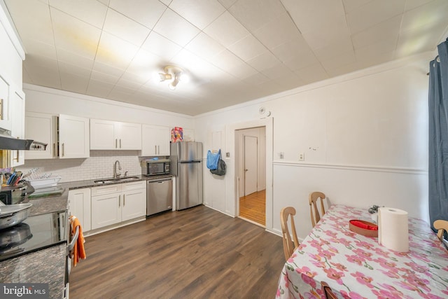 231 N Penn St, West Chester, PA 19380 - kitchen featuring appliances with stainless steel finishes, white cabinetry, dark wood-type flooring, backsplash, and ornamental molding