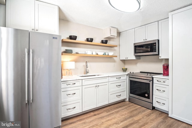 15101 Interlachen Dr Unit 1-126, Silver Spring, MD 20906 - kitchen with stainless steel appliances, light countertops, light wood finished floors, white cabinetry, and a textured ceiling
