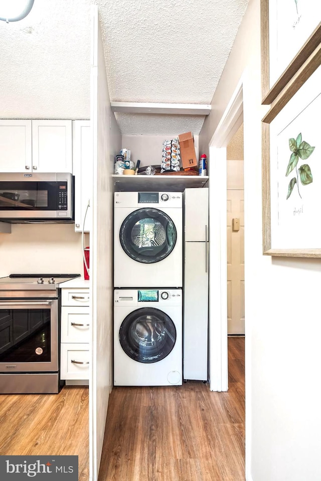 15101 Interlachen Dr Unit 1-126, Silver Spring, MD 20906 - laundry area featuring stacked washer / dryer, light wood-style floors, and a textured ceiling