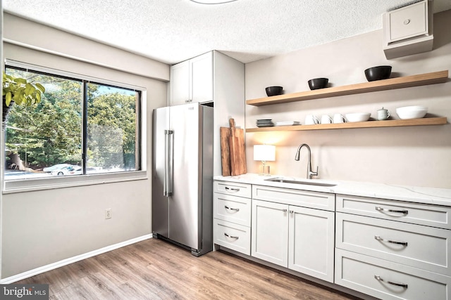 15101 Interlachen Dr Unit 1-126, Silver Spring, MD 20906 - kitchen with freestanding refrigerator, light wood-type flooring, open shelves, a textured ceiling, and light stone counters