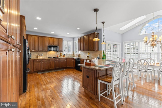 102 Windsor, Swedesboro, NJ 08085 - kitchen with black appliances, a peninsula, a chandelier, brown cabinets, and light wood-type flooring