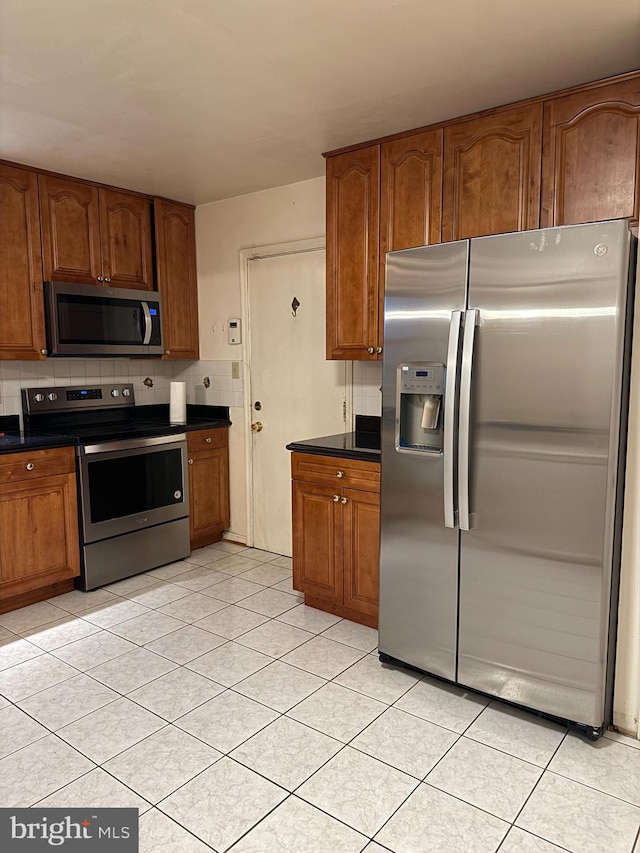 12130 Ambleside Dr, Potomac, MD 20854 - kitchen with stainless steel appliances, dark countertops, brown cabinetry, and light tile patterned floors