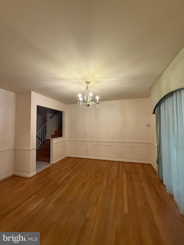 12130 Ambleside Dr, Potomac, MD 20854 - unfurnished room featuring stairway, wood finished floors, a decorative wall, a wainscoted wall, and a chandelier