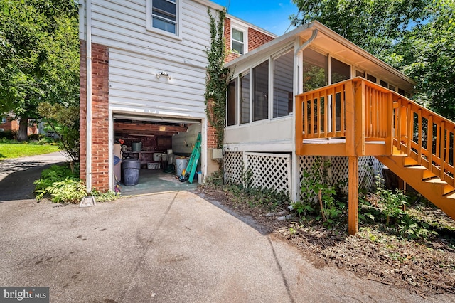 808 Olmstead Rd, Baltimore, MD 21208 - view of side of property featuring a garage, a sunroom, asphalt driveway, stairway, and brick siding